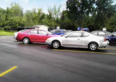 Cars parked along a newly paved parking lot with yellow lane markings