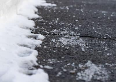 Deicing agent application on asphalt surface with snow and ice