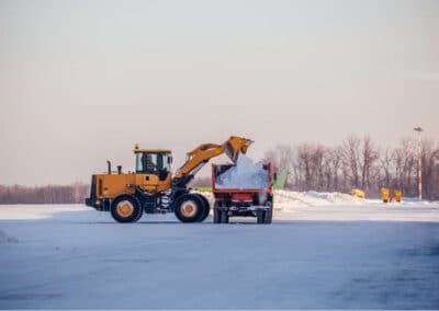 Snow relocation using a wheel loader and dump trailer on a flat surface
