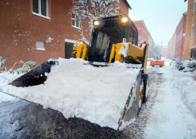 Snow removal with a large snow plow pushing snow off a residential street