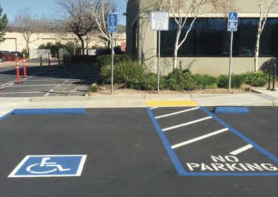 Paved parking lot with a blue handicapped parking space and no-parking area in front of an office building