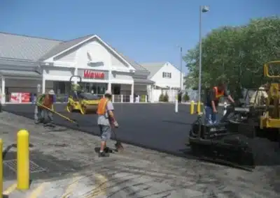 Crew paving a parking lot with asphalt in front of a building