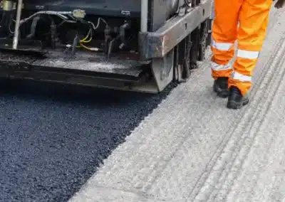 Road paving machine spreading fresh asphalt along a roadway