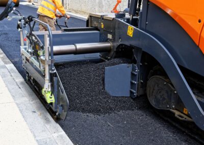 Crew laying fresh asphalt along the street near the curb