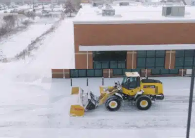 Snow removal using a front-end loader with a snow plow attachment in a parking lot