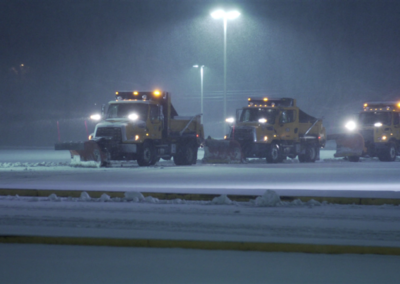 Snowplow trucks parked in a snow-covered area at night