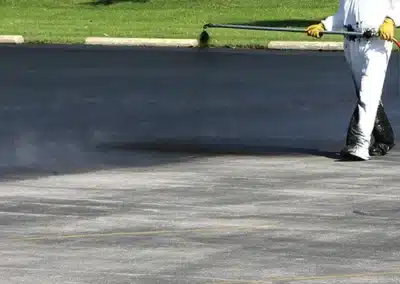 Crew applying spray seal coating to a paved parking lot